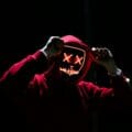 A spooky illuminated mask figure with a red hoodie in a dark setting, perfect for Halloween themes.