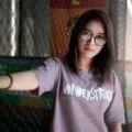 Portrait of a young woman wearing eyeglasses and a 'Wonderstruck' t-shirt posing indoors.