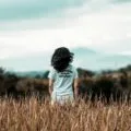 Young woman enjoying a serene moment in a wheat field during summer.