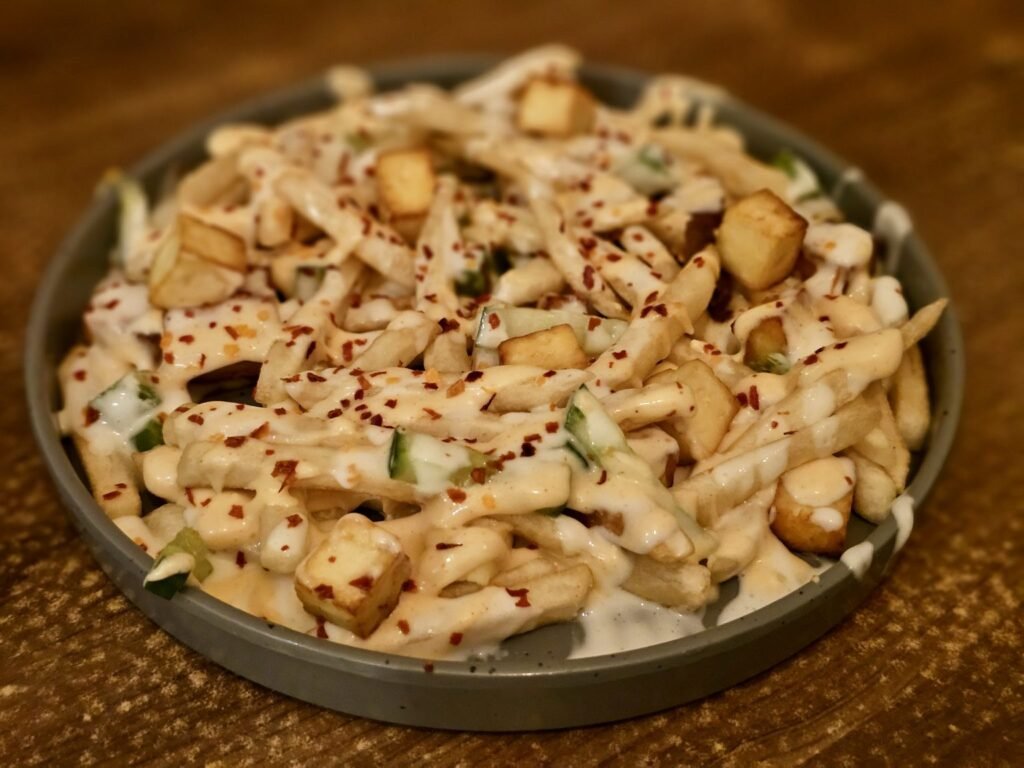 Loaded fries dengan saus, paneer, dan taburan cabai untuk inspirasi menu kafe