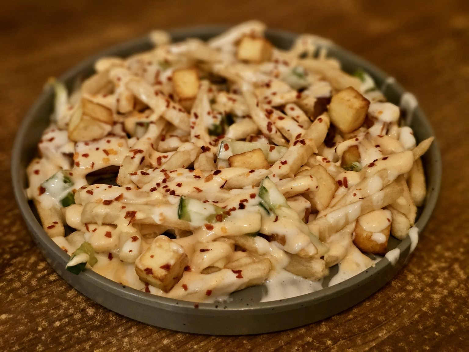 Loaded fries dengan saus, paneer, dan taburan cabai untuk inspirasi menu kafe